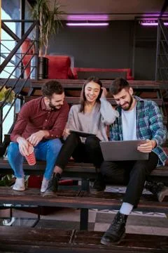 Three charismatic young office workers working hard using tablet and notebook to Stock Photos