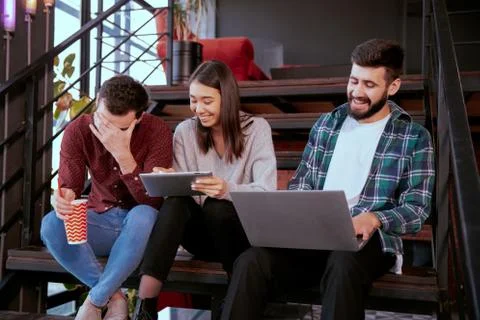 Three charismatic young office workers working hard using tablet and notebook to Stock Photos