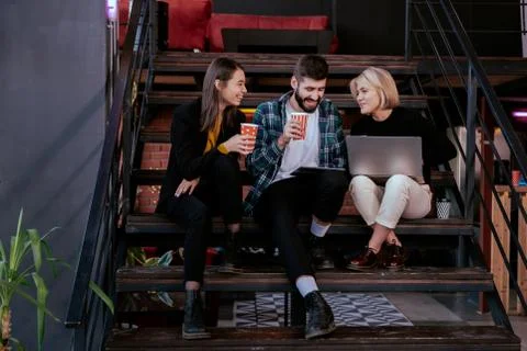 Three charismatic young office workers working hard using tablet and notebook to Stock Photos