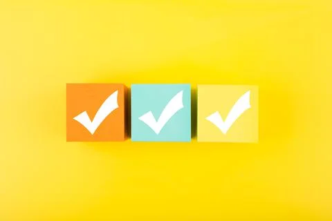 Three checkmarks on colorful blocks against bright yellow background Stock Photos