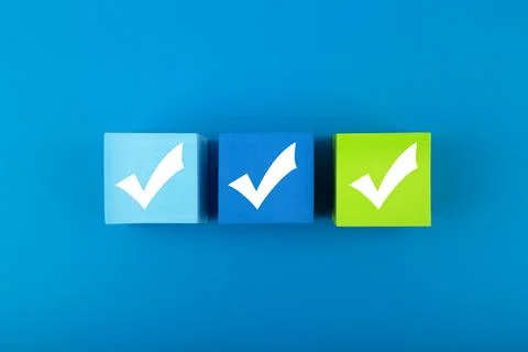 Three checkmarks on toy blocks in the middle of blue background Stock Photos