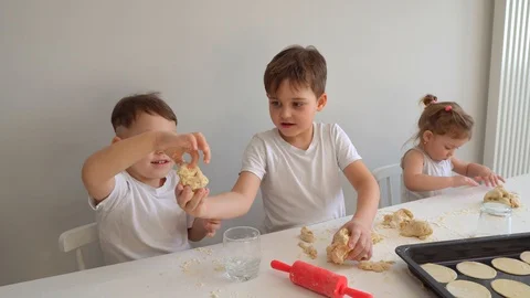 Three cheerful children of different ages kneads the dough. Video stock 128828515