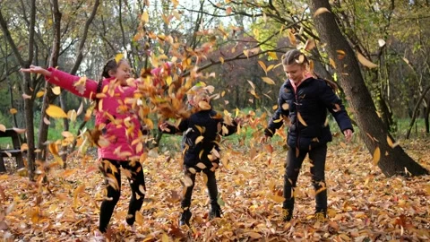 Three cheerful children throw yellow leaves in an autumn Park. Stockbeeldmateriaal 143385192