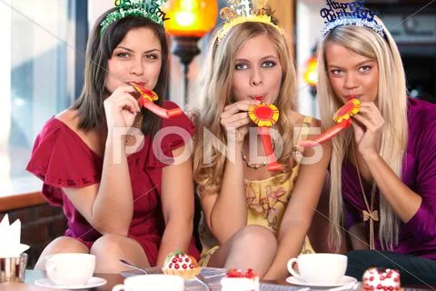 Three cheerful girlfriends with party horn blowers Stock Photos