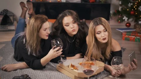 Three cheerful multiracial friends take a selfie on the phone and lie on the rug Stock Footage 101636166