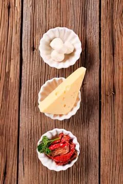 Three cheese and meat appetizers on wooden board Stock Photos