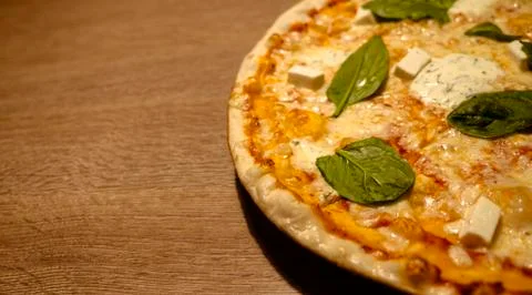 Three cheese thin crust freshly baked pizza with basil leaves on top on a wooden Stock Photos