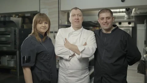Three chefs in black and white uniforms in restaurant kitchen. Slow motion Video stock 241691780