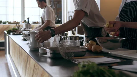 Three chefs peeling potatos, slicing ontions and moving bowls in interior kitche Stock Footage 199457217