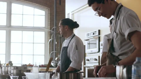 Three chefs standing by their stations ready to cook in interior kitchen with so Stock Footage 199457734
