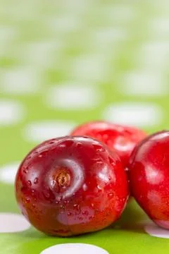 Three cherries on the table cloth with blurred background Foto stock
