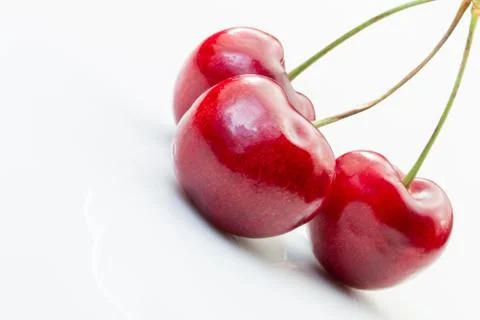 Three cherries on a white background. Stock Photos
