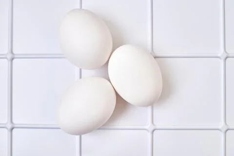 Three chicken bird eggs on a plastic checkered shelf in fridge Stock Photos
