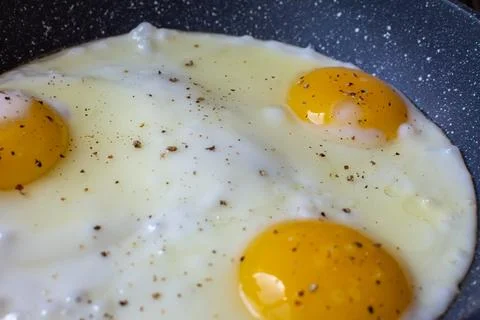 Three chicken eggs are cooked in a frying pan Stock Photos