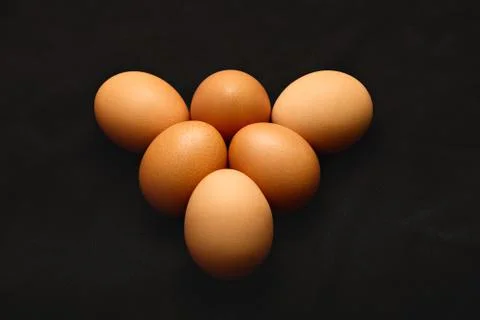 Three chicken eggs on a black background. Close up Stock Photos