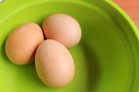 Three chicken eggs isolated white and green background. Фото