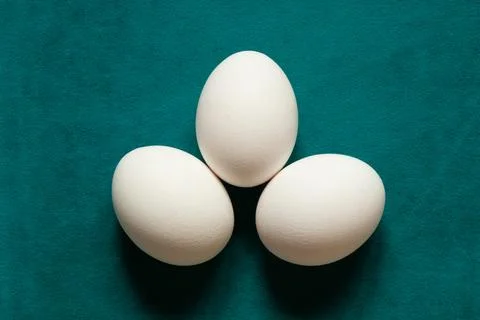 Three chicken eggs lying on a blue surface. The theme is cooking, recipe in.. Stock Photos