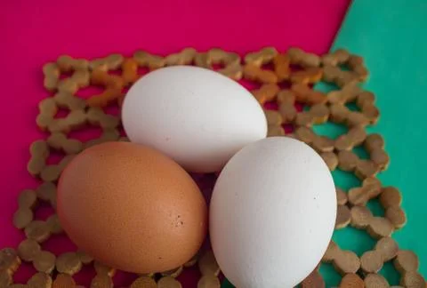 Three chicken eggs on table with green, turquoise and red background. Stock-Fotos