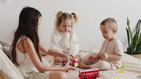 Three children are engaged in play on a soft surface. They build with colorful Video stock 336459593
