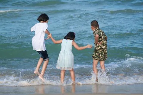 Three children are having fun walking along the beach. Stock Photos