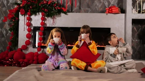 Three children are sitting by the fireplace near the New Year tree. Stock Footage 291009322
