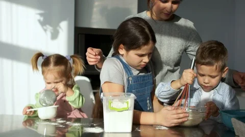 Three children of different ages knead the dough. Elder sister to the flour in a Stock Footage 86805182