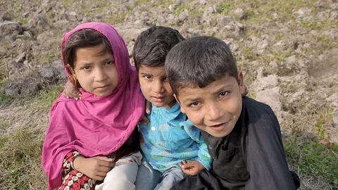 Three children enjoy each others company on a farm in a Pakistan village Stock Footage