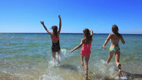 Three children having fun on a beach running to the sea slow motion 스톡 동영상 154355941
