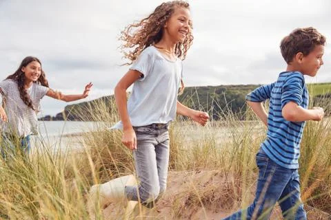 Three Children Having Fun Exploring In Sand Dunes On Winter Beach Vacation Stock Photos