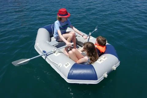 Three children having fun in an inflatable dinghy Stock Photos