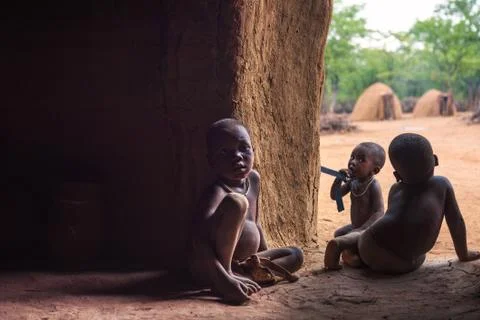 Three children of the Himba tribe in Namibia play in their hut Foto stock
