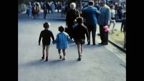 Three children holding hands and walking in the 60s Stock Footage 205592698
