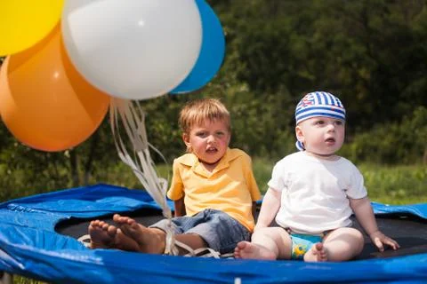 Three children jumping on a trampoline in front of their home Stock Photos