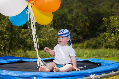 Three children jumping on a trampoline in front of their home Stock Photos