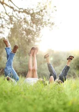 Three children lying in grass with their legs in air Stock Photos