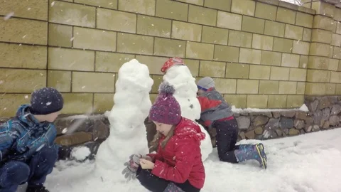 Three children make a snowman. Snowing. 스톡 동영상 74870205