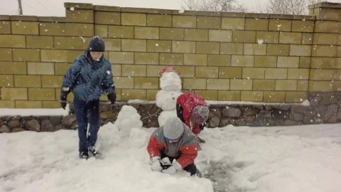 Three children make a snowman. Snowing. 库存影片 74870246