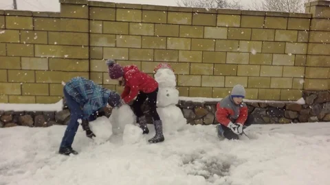 Three children make a snowman. Snowing. 库存影片 74870334