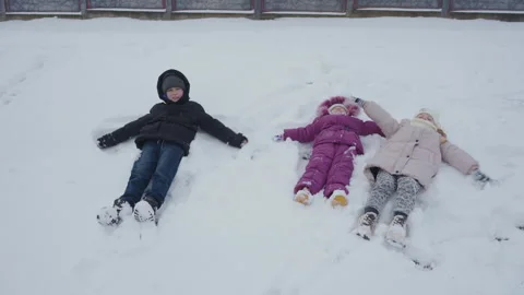 Three children making snow angels Stock-Footage 323314683