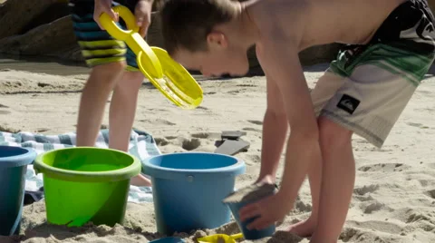 Three children play in sand with beach toys Stock Footage 62489858
