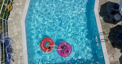 Three children playing on inflatable floats in the swimming pool  Stock Footage 107956249