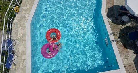 Three children playing in the swimming pool on inflatable rings Stock Footage 107955493