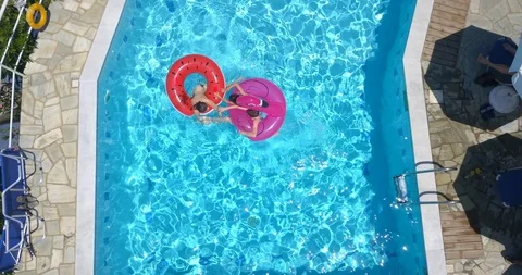 Three children playing in the swimming pool on inflatable rings Stock Footage 107980575