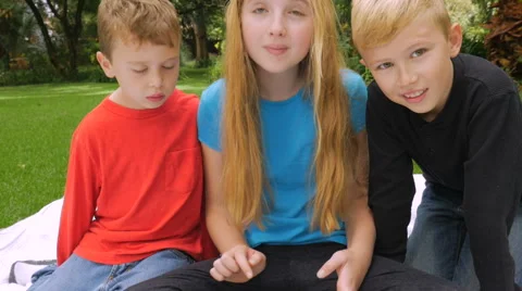 Three children playing on a tablet while one swats a mosquito - push-in shot Stock Footage 68091677