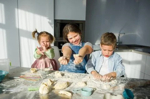 Three children prepare something from the dough. Stock Photos