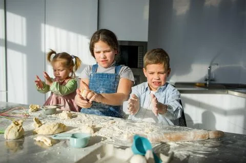 Three children prepare something from the dough. Stock Photos