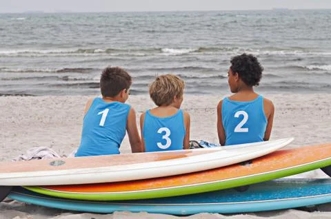 Three children sitting on the beach Stock Photos