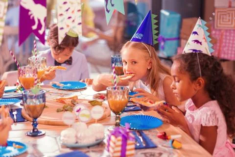 Three children sitting silently while eating tasty food Stock-Fotos