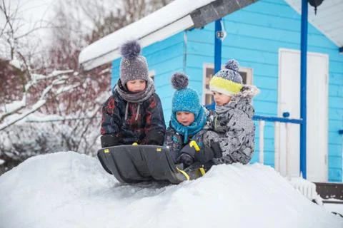 Three children sledding in winter Stock Photos