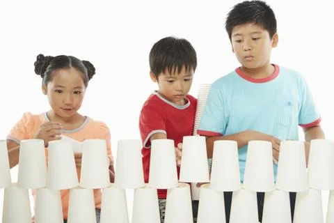 Three children stacking up disposable cups together Stock Photos